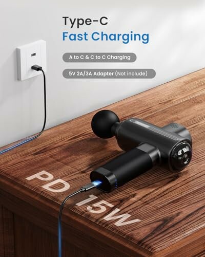 Pistolet de massage avec charge rapide Type-C sur une table en bois.